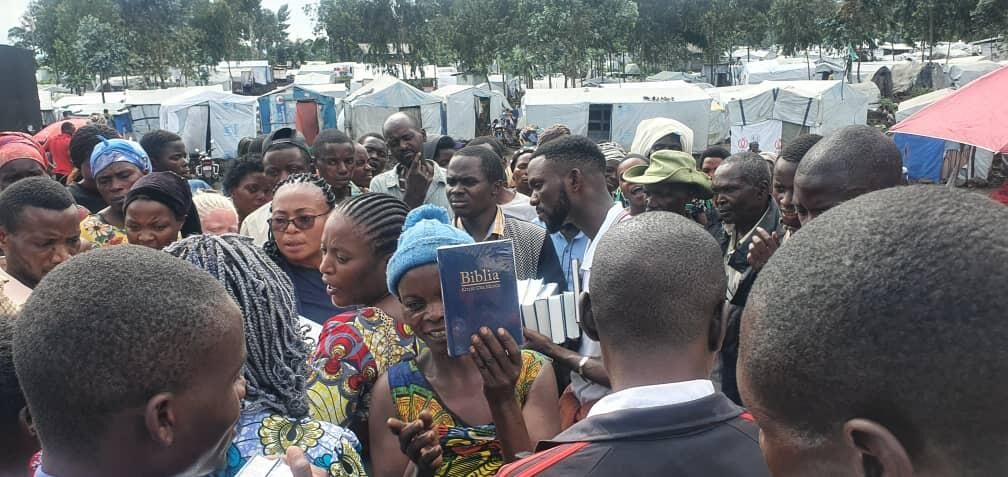NCE staff distributing tarpaulins to women at a camp